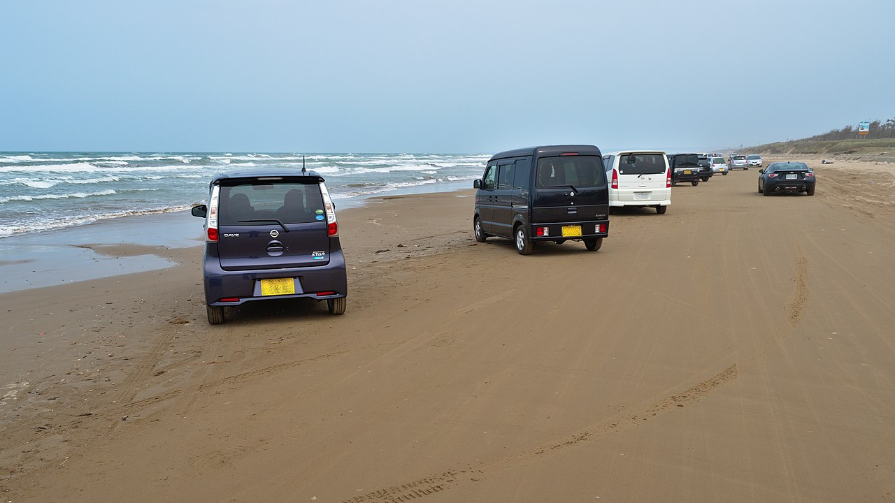 千里浜なぎさドライブウェイの砂浜を走る車と日本海の風景