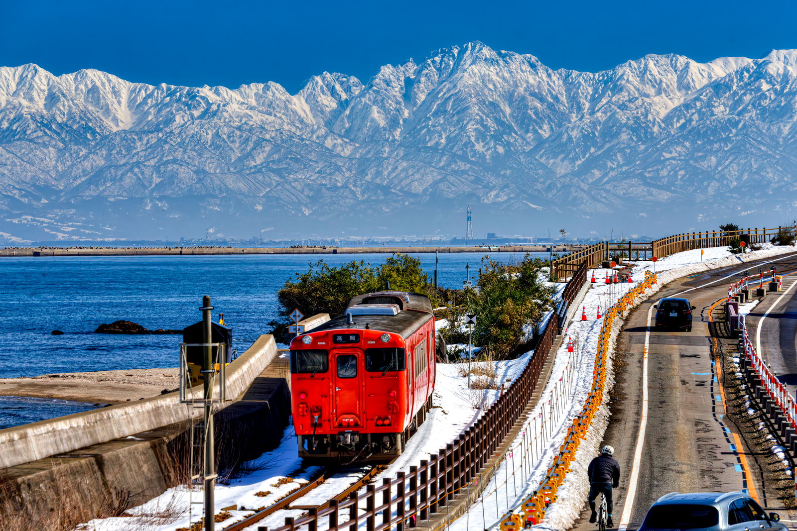 冬の雨晴海岸を走る氷見線キハ47と雪を頂いた立山連峰