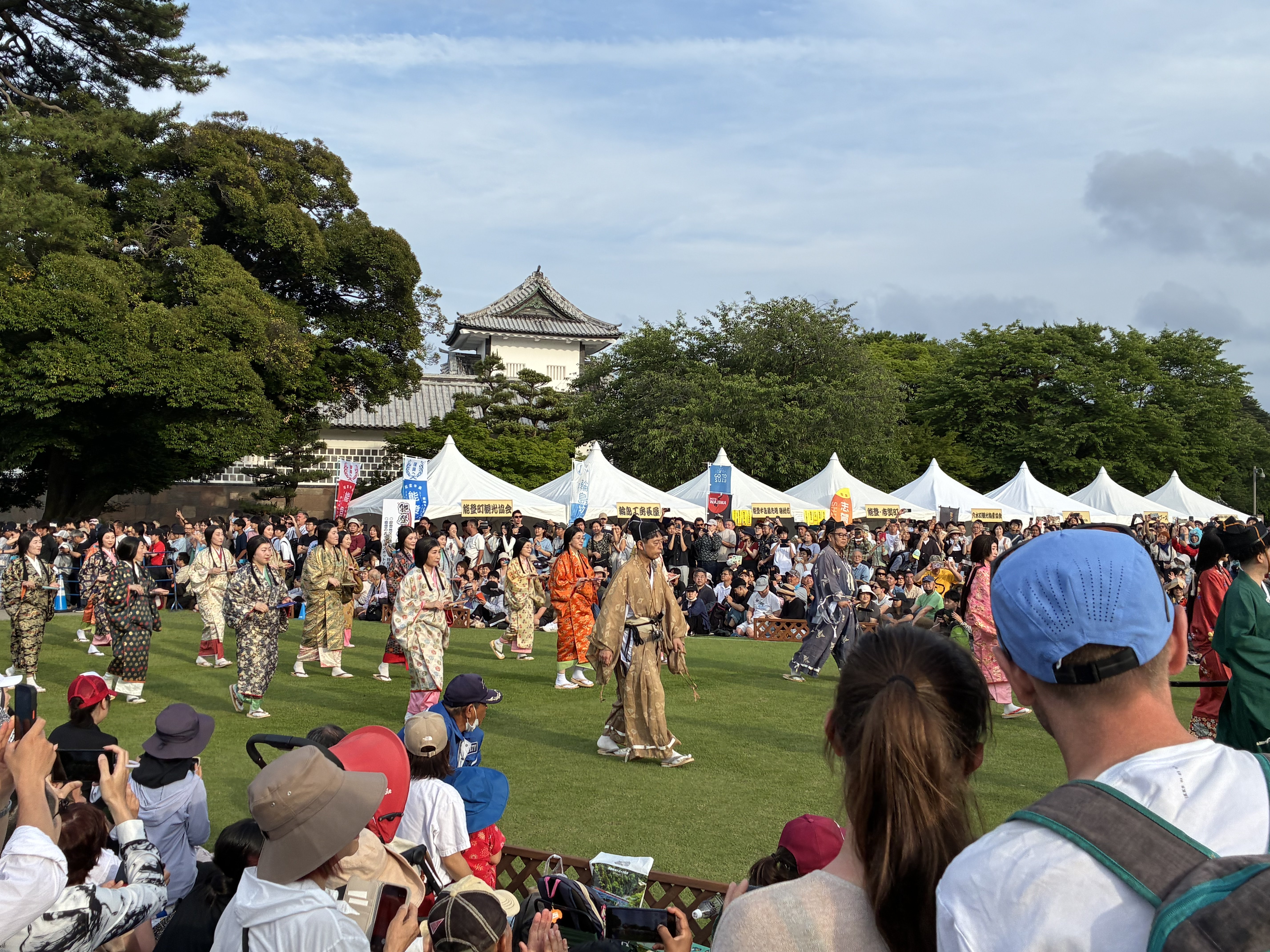 色とりどりの衣装の行列が金沢城公園を練り歩く。満員の観客席