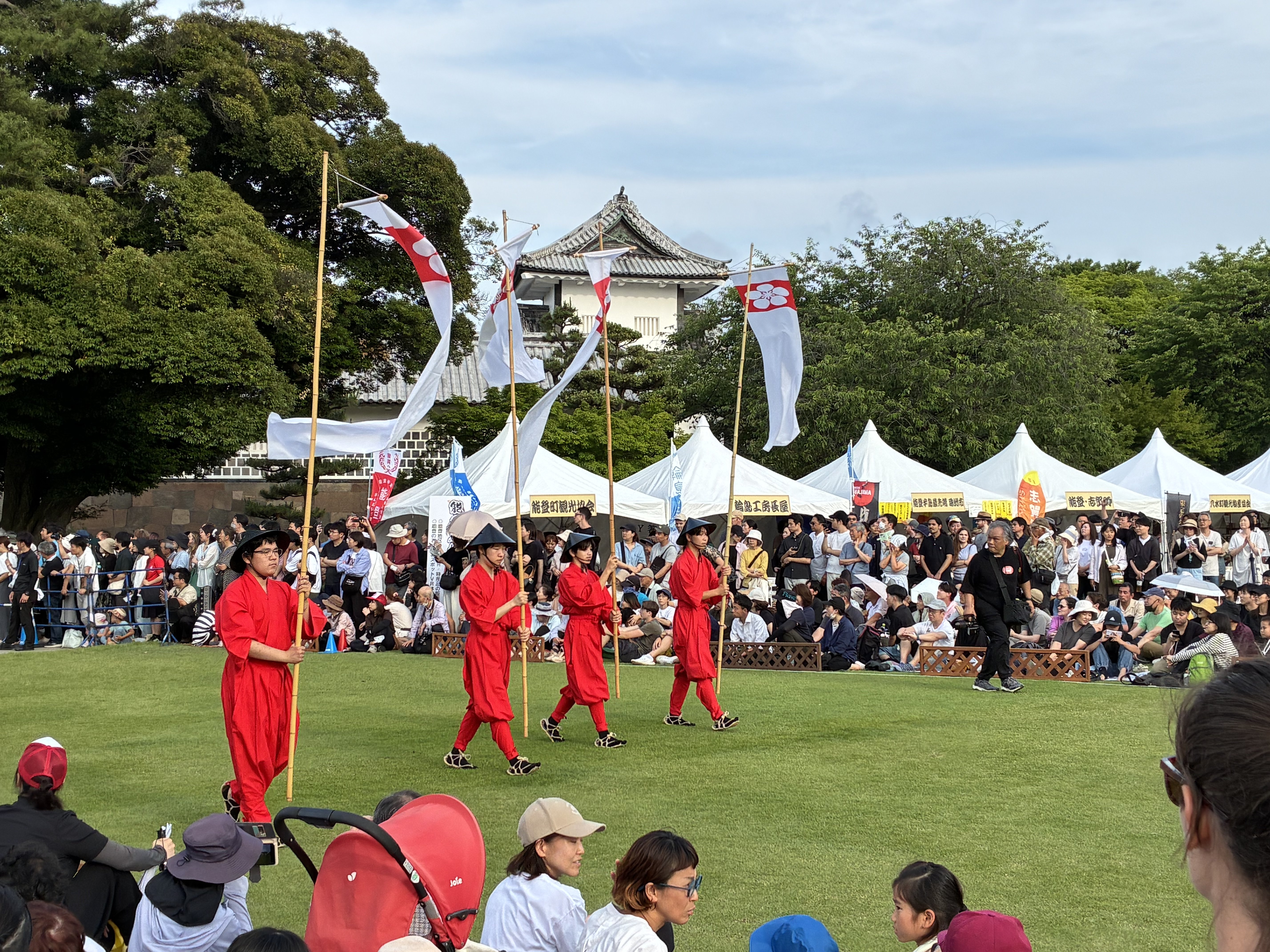 金沢城公園・三の丸広場で白旗をなびかせる行列と城の天守