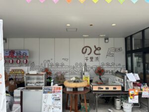 道の駅のと千里浜の軒下に並ぶ焼だんごや醤油フランクの屋台コーナーと施設名の壁画