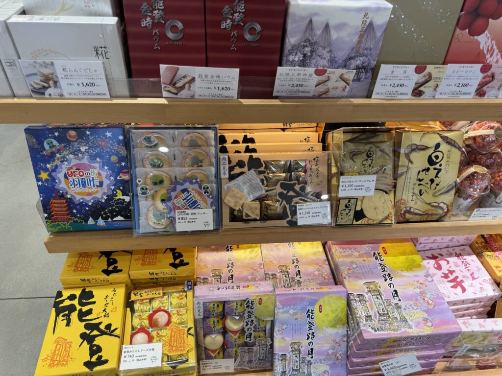能登金時バウムや白えびせんべい、UFOの街羽咋クッキーが並ぶみやげ菓子の棚