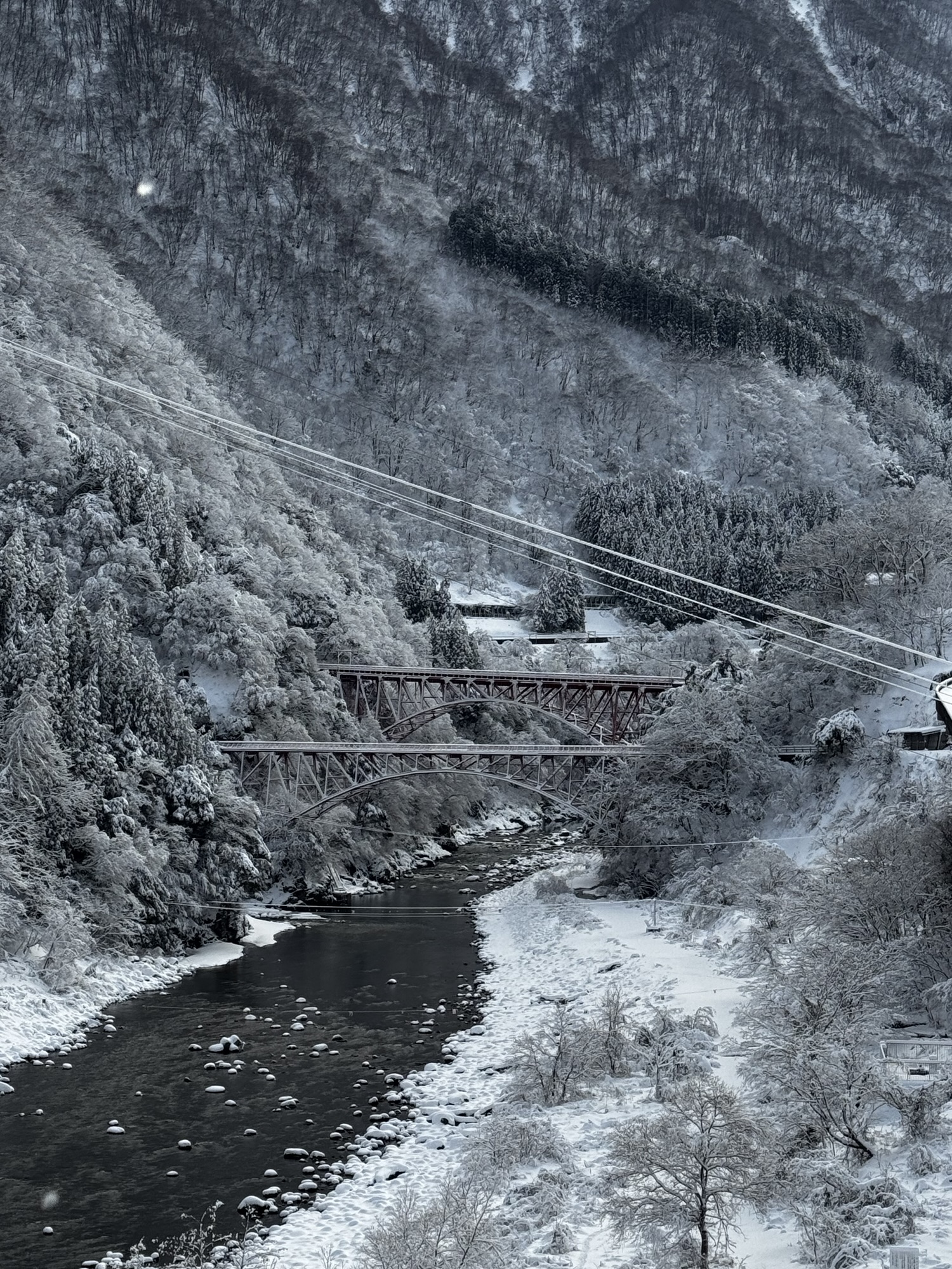 雪の黒部峡谷に架かる2本の赤い鉄橋(新山彦橋と山彦橋)