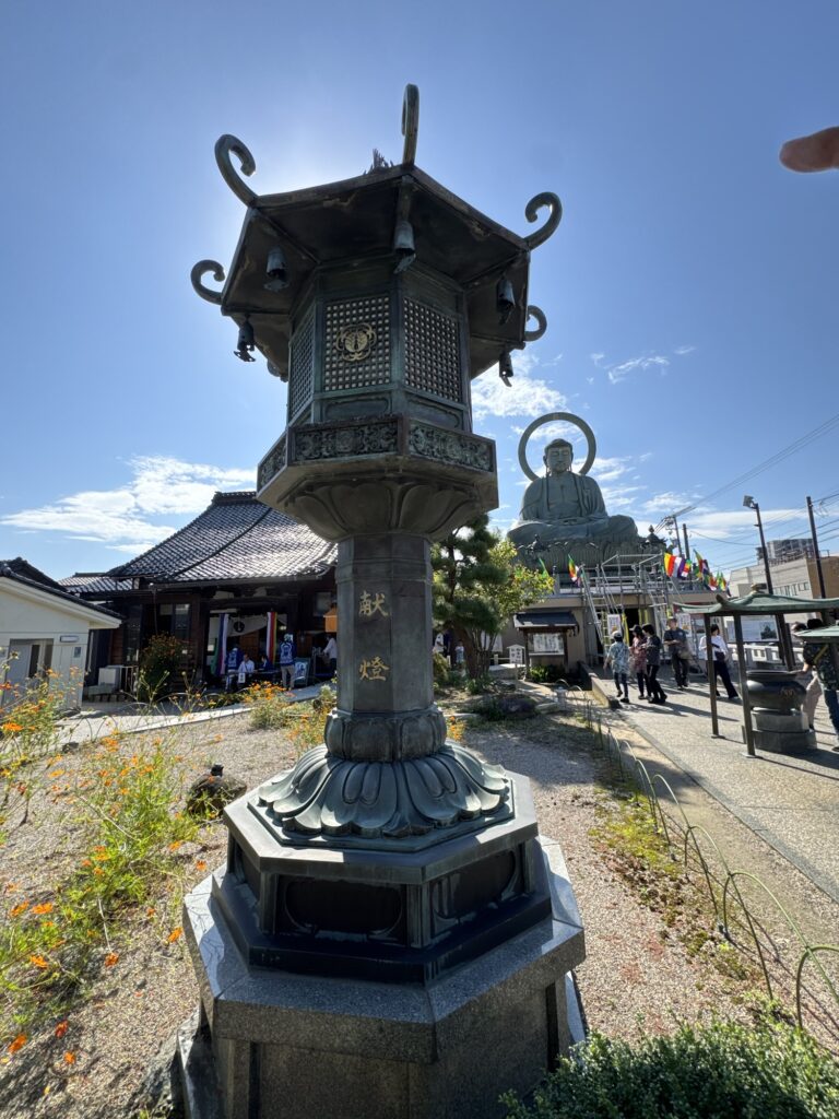 「献燈」と刻まれた燈籠越しに見る高岡大仏と境内